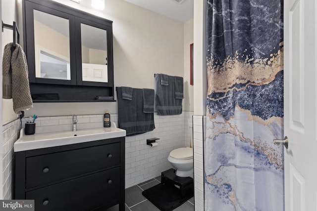 bathroom featuring vanity, tile patterned floors, toilet, tile walls, and walk in shower