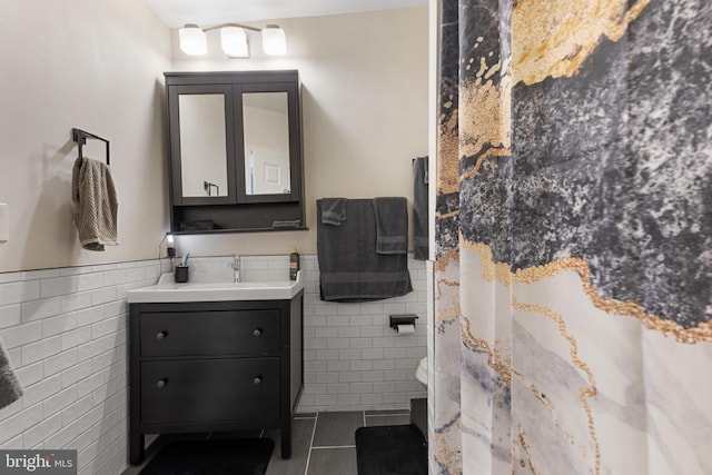 bathroom with tile patterned floors, curtained shower, vanity, and tile walls