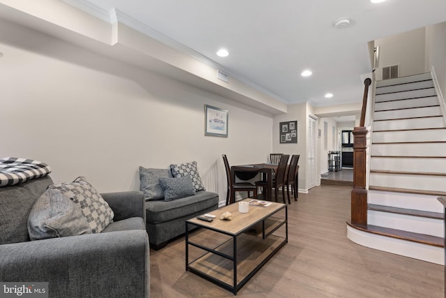 living room with wood-type flooring and ornamental molding