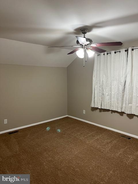 empty room with lofted ceiling, ceiling fan, and carpet floors