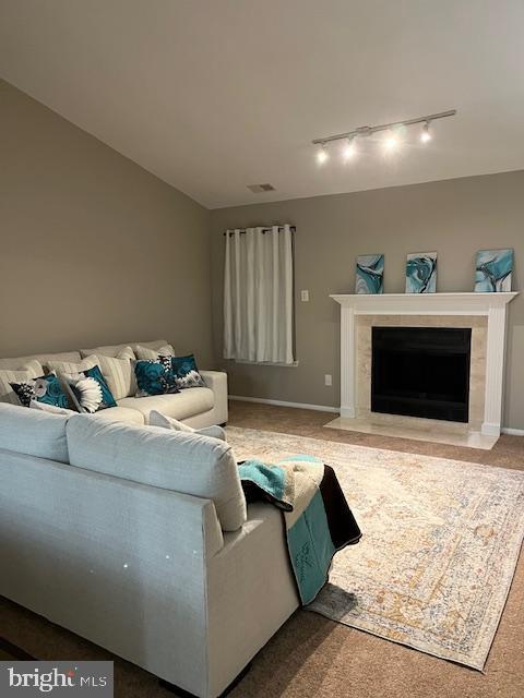 carpeted living room featuring a high end fireplace and track lighting