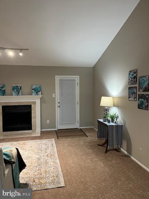 carpeted living room with a fireplace, rail lighting, and vaulted ceiling