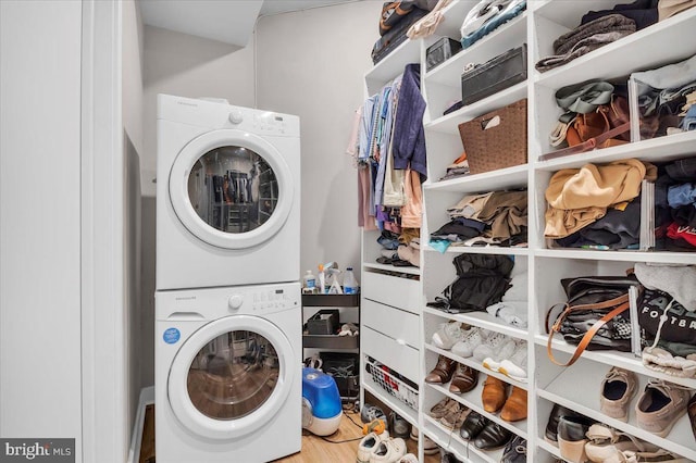 laundry room with stacked washer and clothes dryer and wood-type flooring