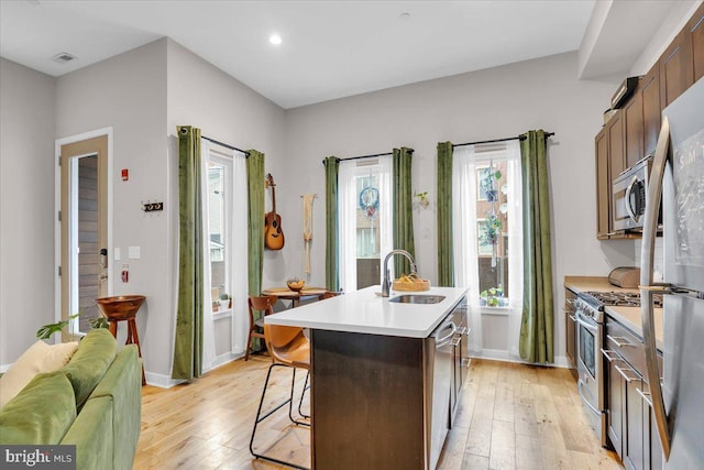 kitchen featuring sink, stainless steel appliances, light wood-type flooring, and a kitchen island with sink