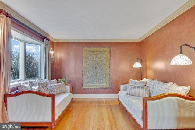 sitting room with ornamental molding and light hardwood / wood-style flooring