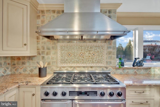 kitchen featuring cream cabinetry, island exhaust hood, light stone counters, and stainless steel gas stove