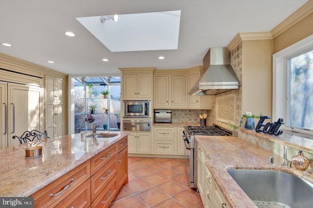 kitchen with sink, wall chimney range hood, stainless steel appliances, light stone countertops, and tasteful backsplash