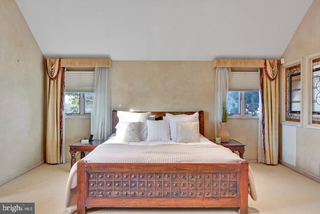 bedroom with vaulted ceiling and light colored carpet