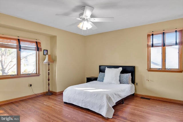 bedroom featuring multiple windows, wood-type flooring, and ceiling fan