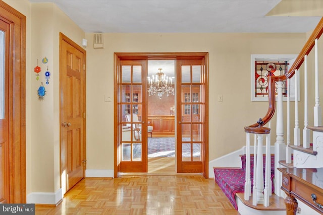 entrance foyer with french doors, a chandelier, and light parquet floors