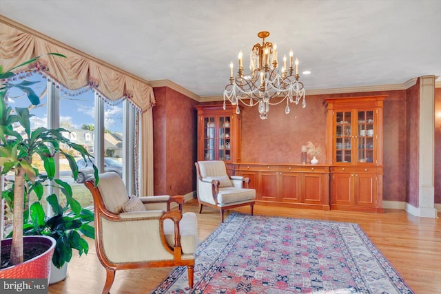 living area featuring ornamental molding, an inviting chandelier, and light hardwood / wood-style flooring