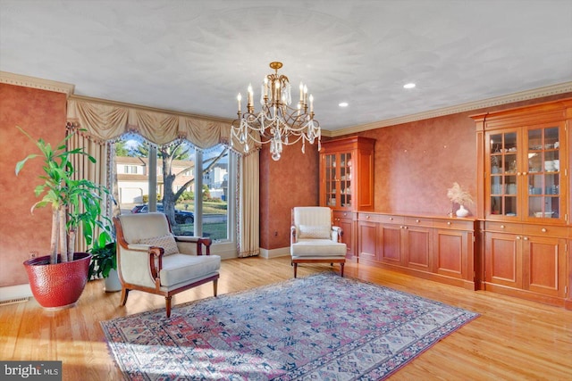 living area with ornamental molding, an inviting chandelier, and light hardwood / wood-style flooring