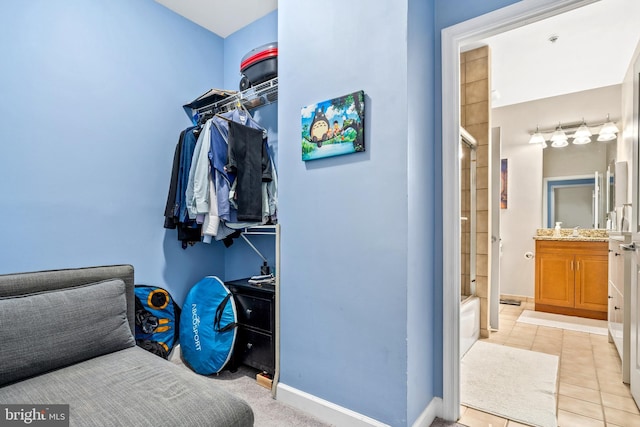 walk in closet with light tile patterned floors and sink