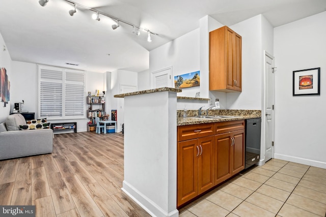 kitchen with dishwasher, light hardwood / wood-style floors, light stone counters, and sink