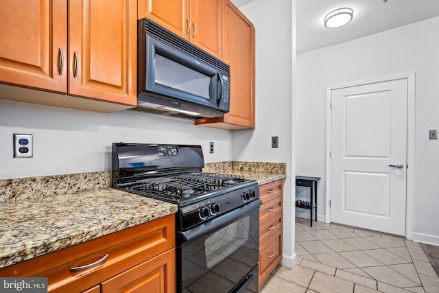 kitchen with black appliances, light tile patterned flooring, and light stone countertops