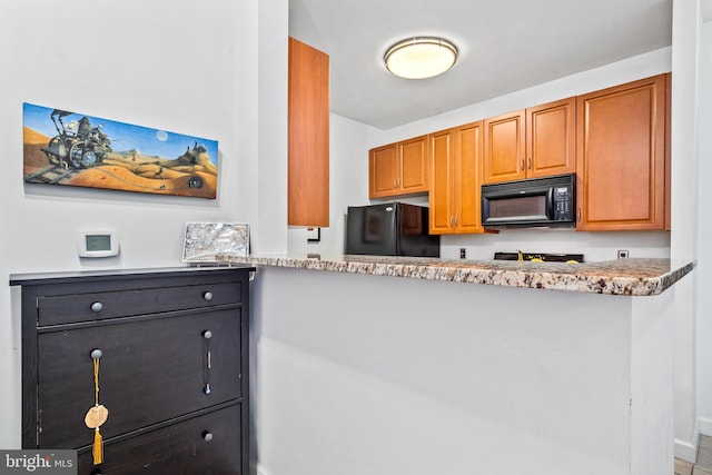 kitchen featuring light stone counters and black appliances