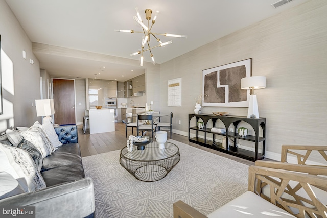 living room with sink, a chandelier, and wood-type flooring