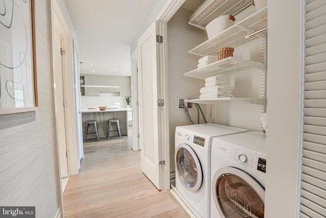 laundry area with light hardwood / wood-style flooring and washing machine and clothes dryer