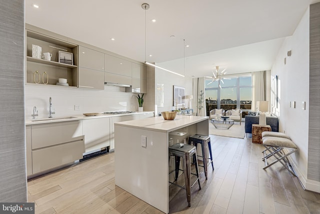 kitchen featuring pendant lighting, backsplash, a kitchen breakfast bar, sink, and a kitchen island