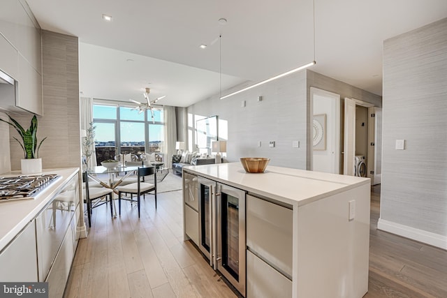 kitchen with washer / dryer, a center island, light hardwood / wood-style flooring, and beverage cooler