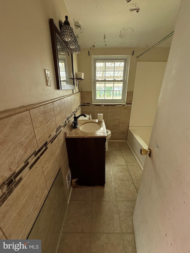 full bathroom featuring washtub / shower combination, vanity, tile walls, tile patterned flooring, and toilet