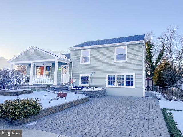 snow covered rear of property with covered porch