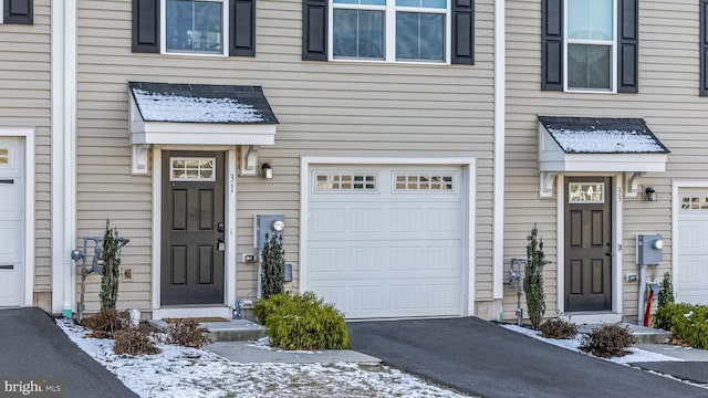 snow covered property entrance featuring a garage