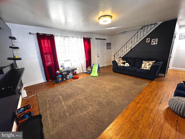 living room with stairs, hardwood / wood-style floors, and baseboards