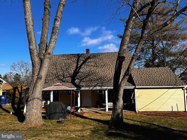 view of front of property with a shingled roof, a chimney, and a front lawn