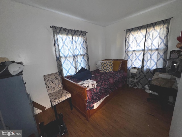 bedroom with multiple windows and wood finished floors