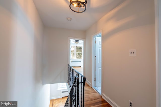 corridor with light wood-type flooring and baseboard heating