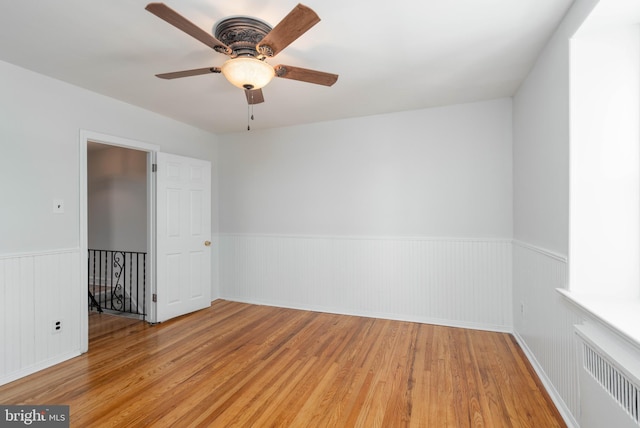 unfurnished room with radiator heating unit, light hardwood / wood-style floors, and ceiling fan