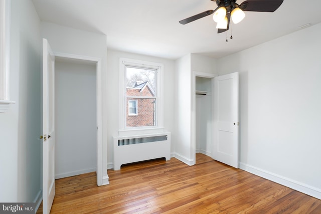 unfurnished bedroom with radiator, ceiling fan, and light wood-type flooring