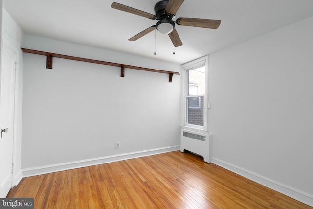 empty room featuring ceiling fan, wood-type flooring, and radiator