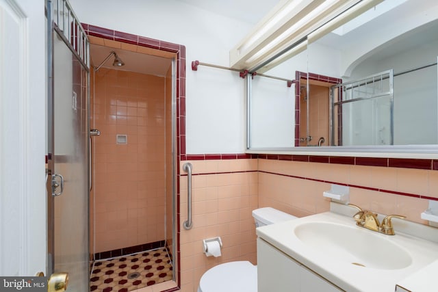 bathroom with toilet, tile walls, vanity, and walk in shower