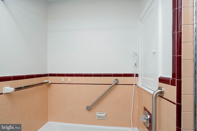 bathroom with a bathtub and tile walls