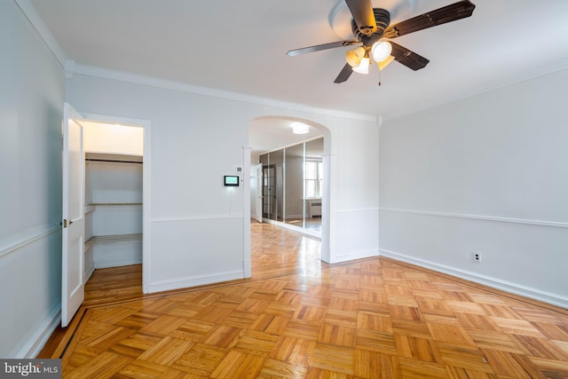 spare room with light parquet floors, ornamental molding, and ceiling fan