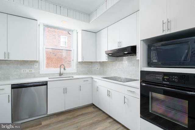 kitchen with sink, white cabinetry, tasteful backsplash, light hardwood / wood-style floors, and black appliances