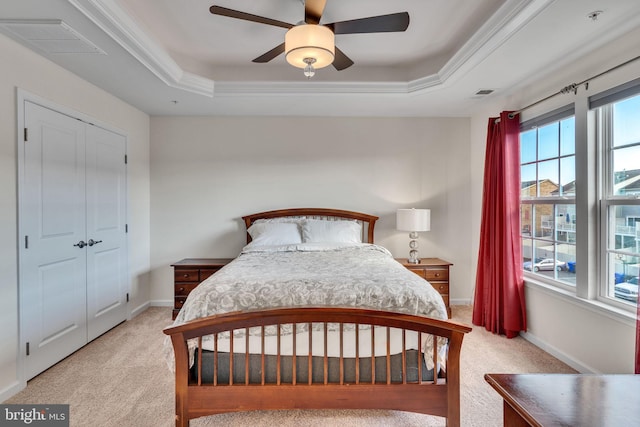 bedroom featuring a closet, a tray ceiling, ceiling fan, and light colored carpet