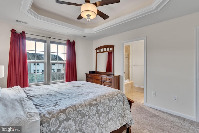 bedroom featuring ceiling fan, a raised ceiling, light colored carpet, and ensuite bathroom