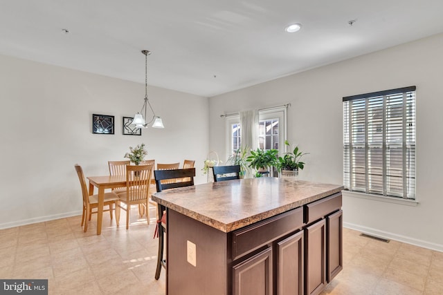 kitchen featuring decorative light fixtures, a center island, dark brown cabinetry, and an inviting chandelier