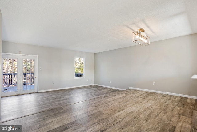 unfurnished room with hardwood / wood-style flooring, a notable chandelier, and a textured ceiling