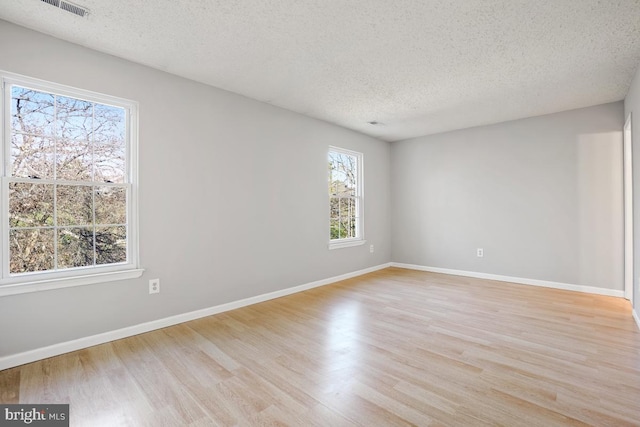 unfurnished room with a textured ceiling and light hardwood / wood-style flooring