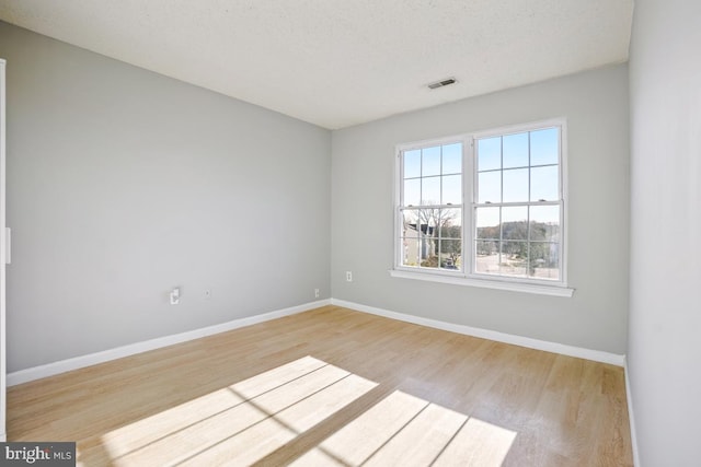 empty room with a textured ceiling and light wood-type flooring