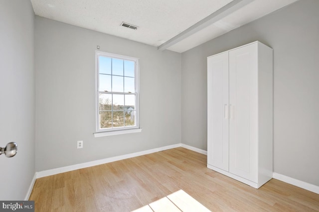 unfurnished bedroom with a textured ceiling, light hardwood / wood-style flooring, and a closet