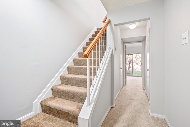 stairs featuring a textured ceiling and carpet floors