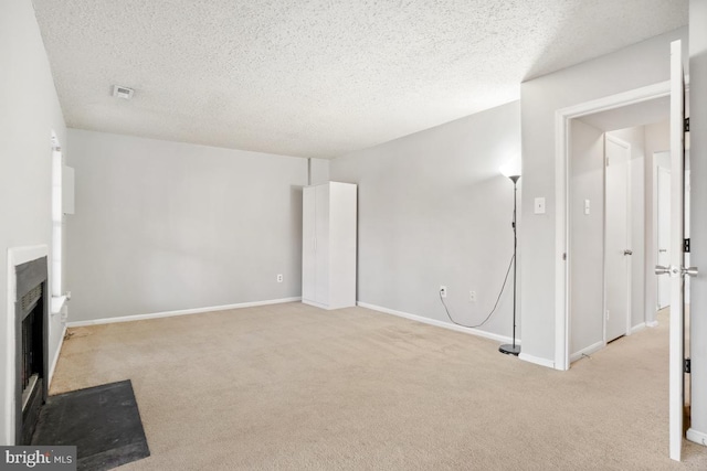 unfurnished living room with light carpet and a textured ceiling