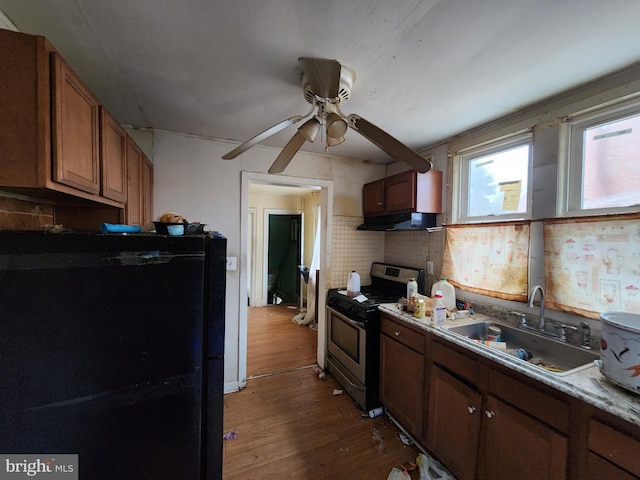 kitchen with sink, black fridge, dark hardwood / wood-style floors, stainless steel range oven, and decorative backsplash