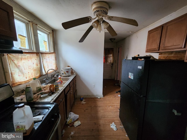 kitchen with stove, black refrigerator, sink, ceiling fan, and light hardwood / wood-style floors