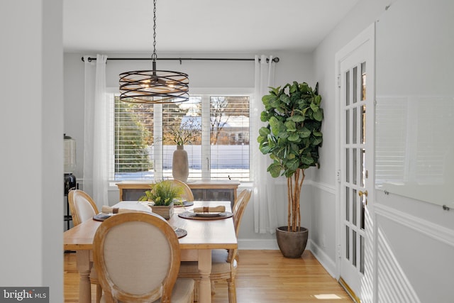 dining space with french doors, light hardwood / wood-style floors, and a notable chandelier